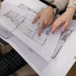 Two people examining architectural blueprints, focusing on project details.